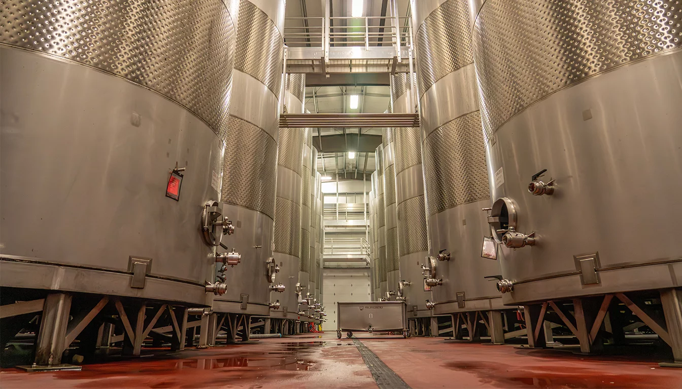 Stainless steel fermentation vessels in an industrial biotechnology production facility representing Dyadic's precision fermentation platform